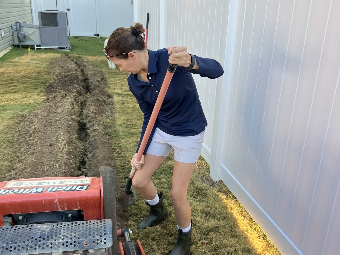 Colette Murray working alongside a walk-behind trencher cutting a drainage line