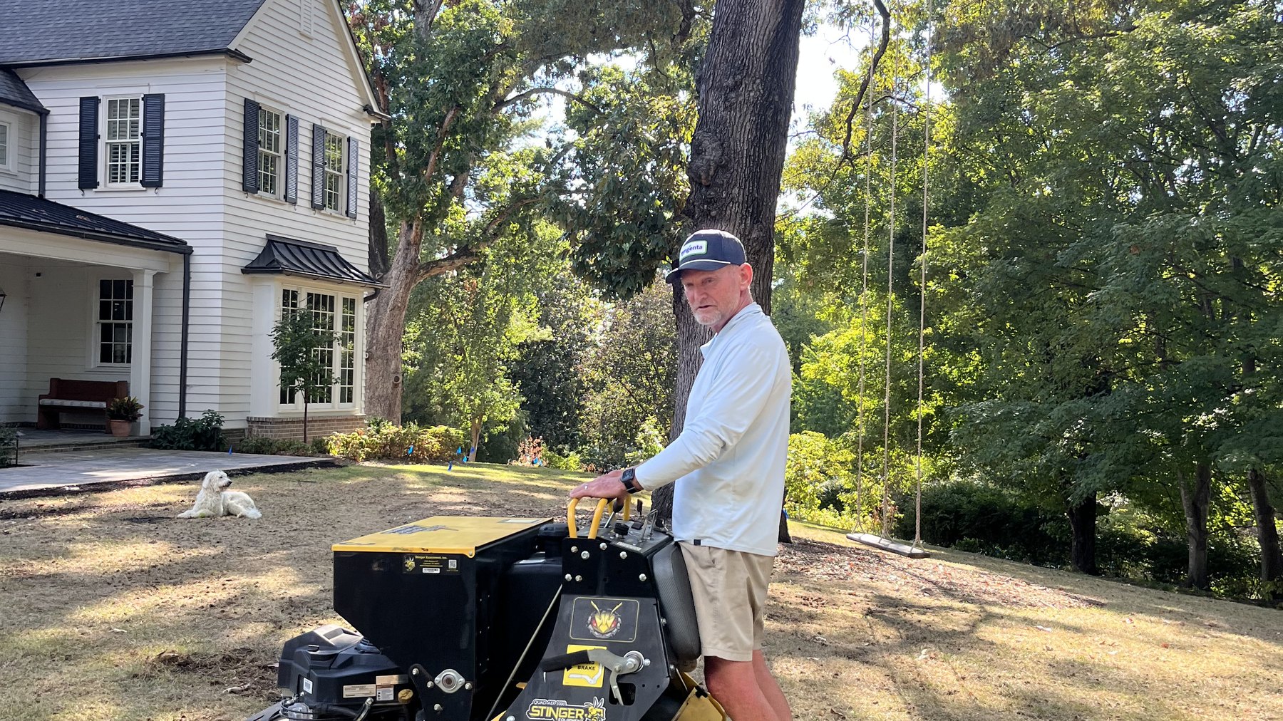 Chip Ward running a stand-on spreader across a large front lawn